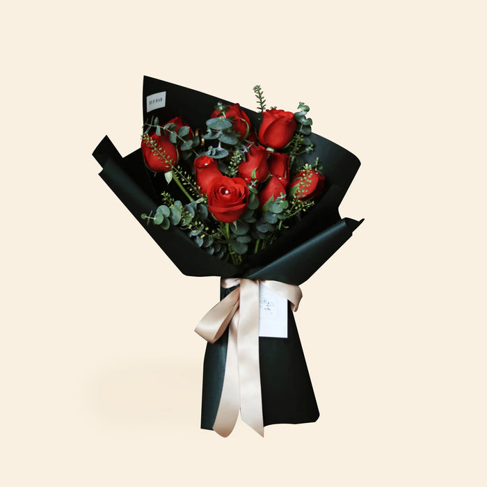Classic red rose bouquet with eucalyptus, wrapped in black paper and tied with a white ribbon