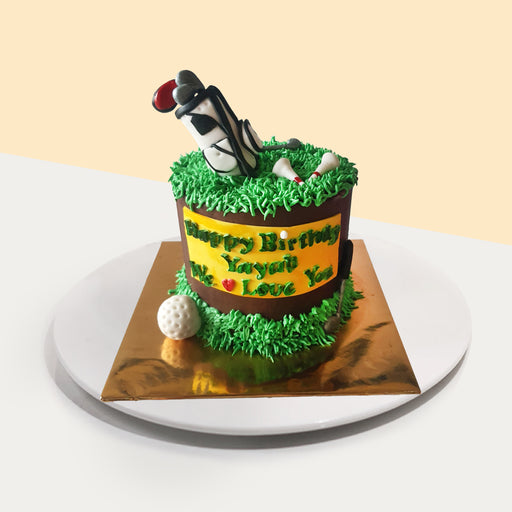 Cake decorated with cream piped grass, and fondant shaped golf bag, gold ball and tees