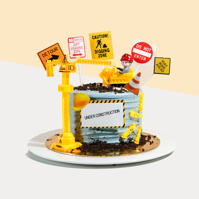 Construction cake decorated with plastic crane, excavator and warning signs