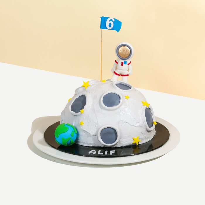 Half sphere cake decorated like a moon, with an astronaut on top