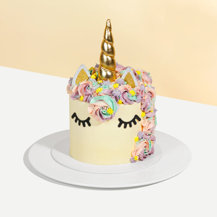 Cake with fake fondant lashes, with rainbow swirls and a unicorn horn
