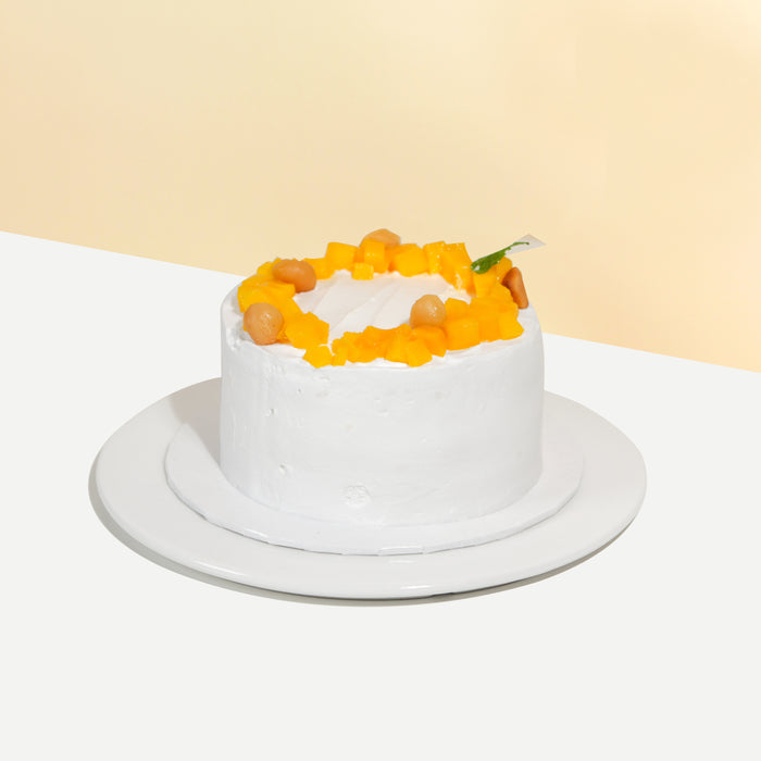 Sponge cake with cream frosting, topped with mangoes and macadamia nuts