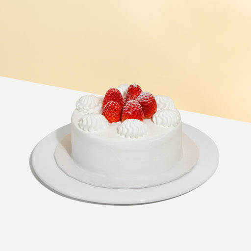 Vanilla sponge cake with signature cream cheese frosting, with fresh strawberries between the layers and on the cake