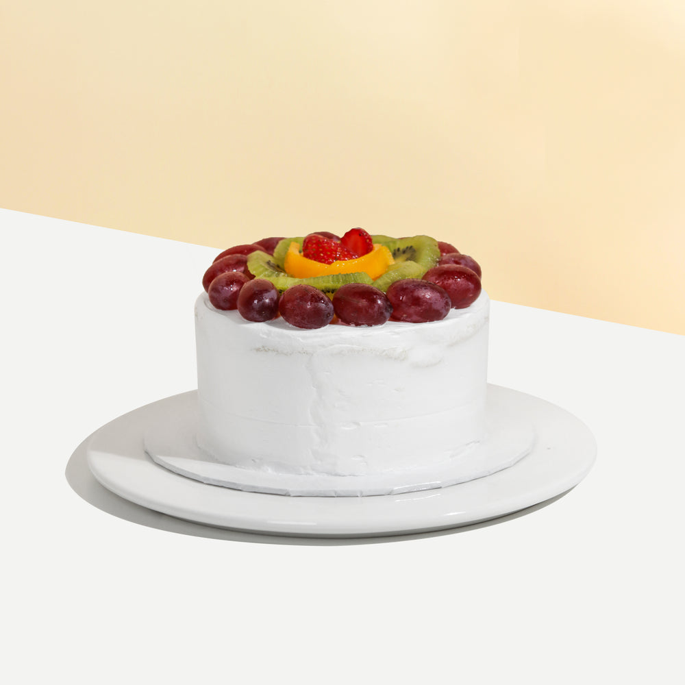 Sponge cake with cream cheese frosting, layered and topped with fresh fruits