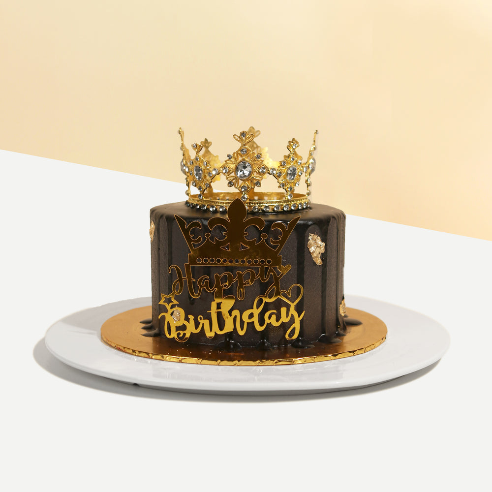 Black buttercream cake, with a golden crown and decorations