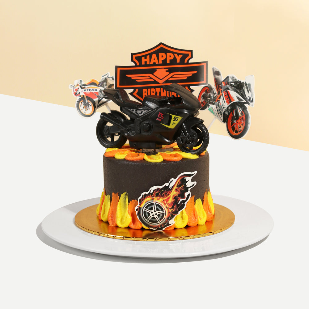 Black buttercream cake with orange and yellow buttercream, with a model bike on top