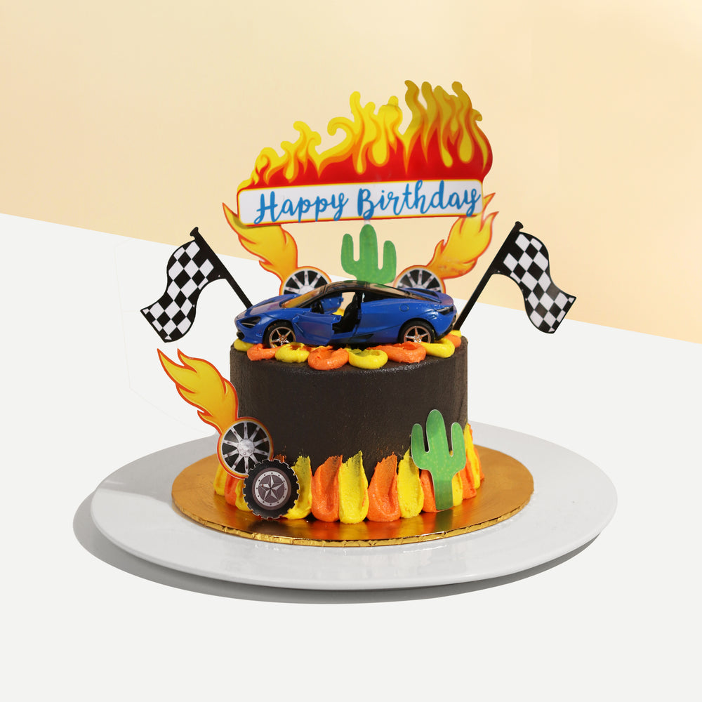 Car themed caked, with a toy car on top, along with 2d printed fire decals, checkered flag and wheels