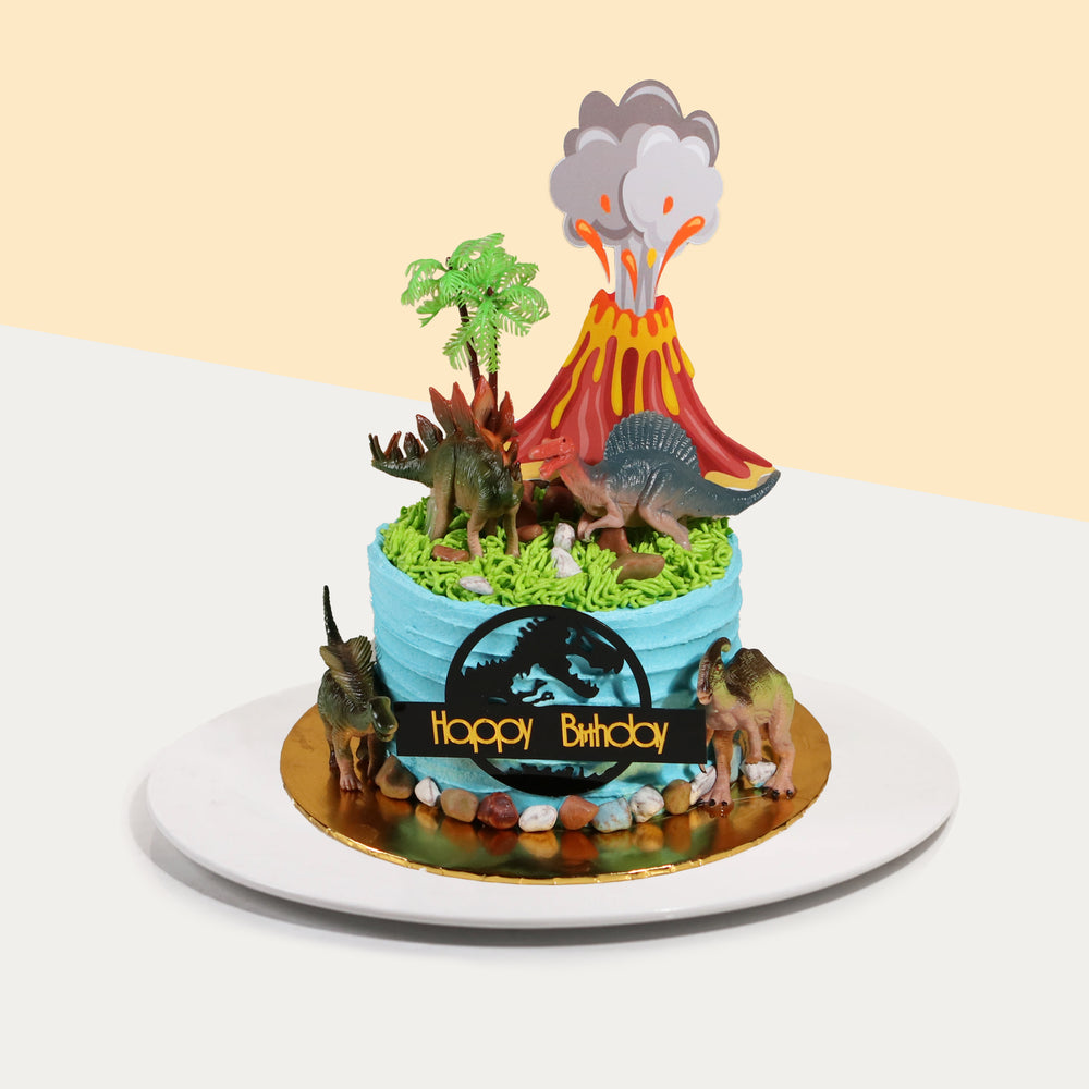 Blue buttercream frosted cake, decorated with dinosaurs and a 2d printed volcano