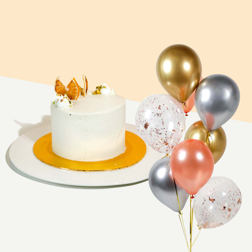 Small cake coated with fresh cream, garnished with dried orange slices and crushed pistachios with a bundle of balloons