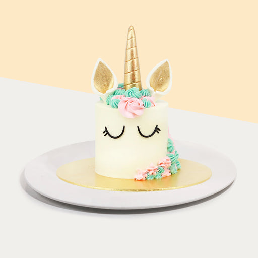 White buttercream frosted cake with unicorn decorations