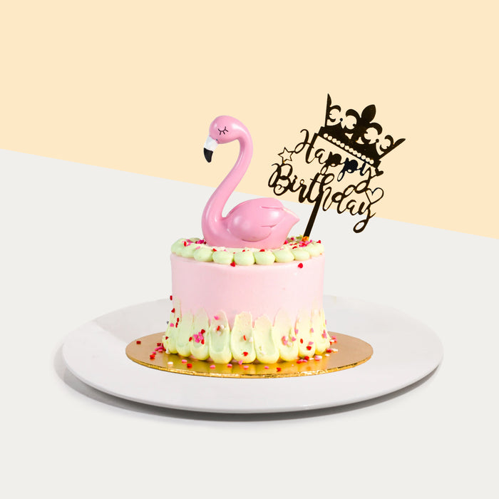 Pink buttercream cake with cream swipes, topped with a plastic flamingo figurine