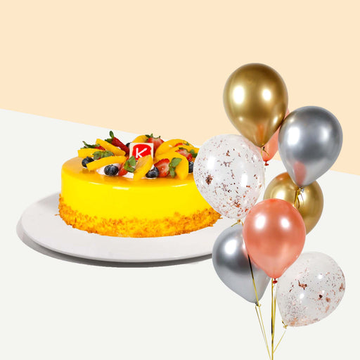 Yellow cake with mango fruit filling, topped with more mangoes, strawberries and blueberries with a bundle of balloons