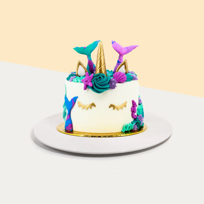 Mermaid unicorn cake, with golden accents for the unicorn, and purple and blue for the mermaid tails