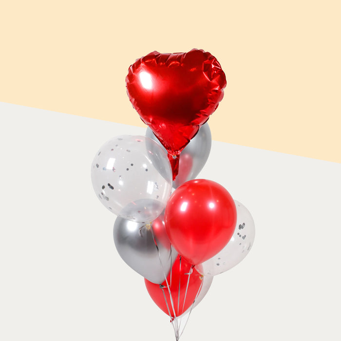 Red themed balloons, with a red foil heart, confetti, red and silver balloons