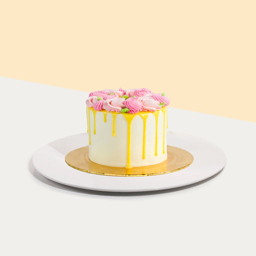 Yellow buttercream cake, with yellow drip, with pink hand-piped swirls