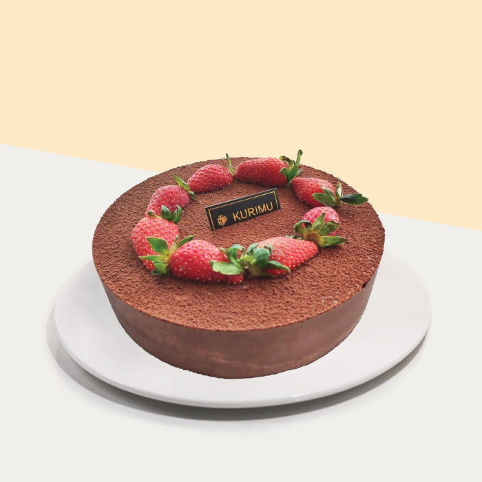 Mousse cake with  cocoa powder over the top, topped with fresh strawvberries