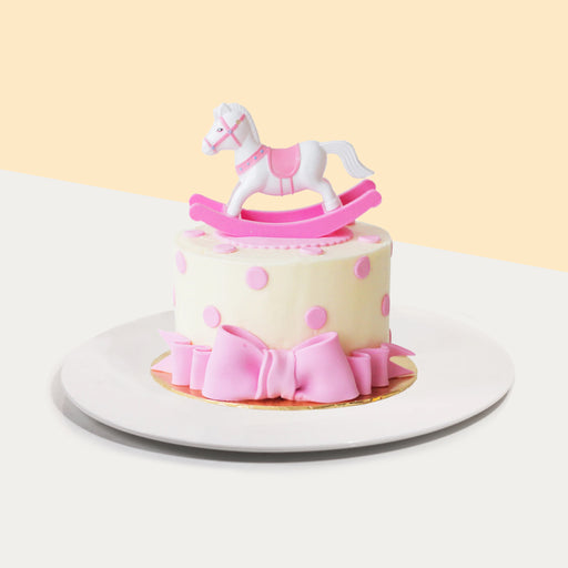 Pink pony themed cake, with a rocking pony figurine, and pink fondant ribbon