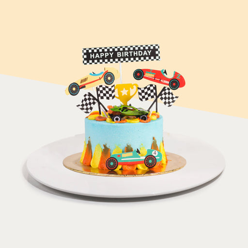 Blue buttercream cake with orange and yellow cream swipes, topped with a toy car model