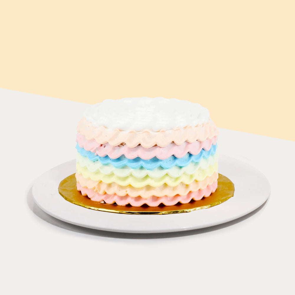 Rainbow sponge cake decorated with rainbow cream ruffles