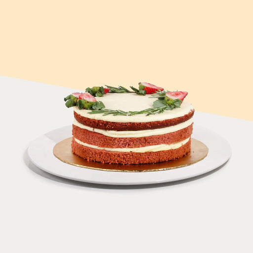 Red velvet cake with vanilla cream cheese frosting, topped with fresh herbs and strawberries