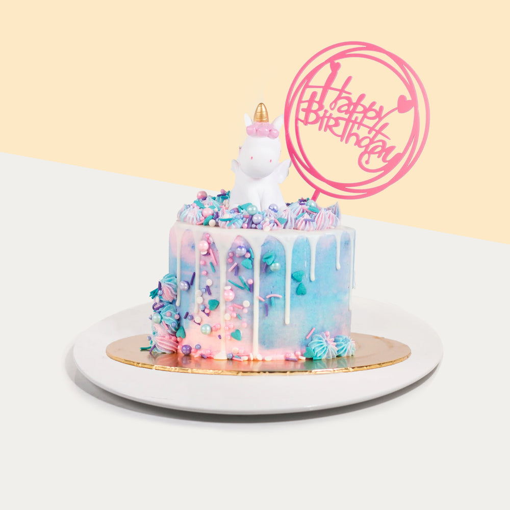 Blue and pink cake, decorated with edible pearls, chocolate sprinkles and a unicorn toy