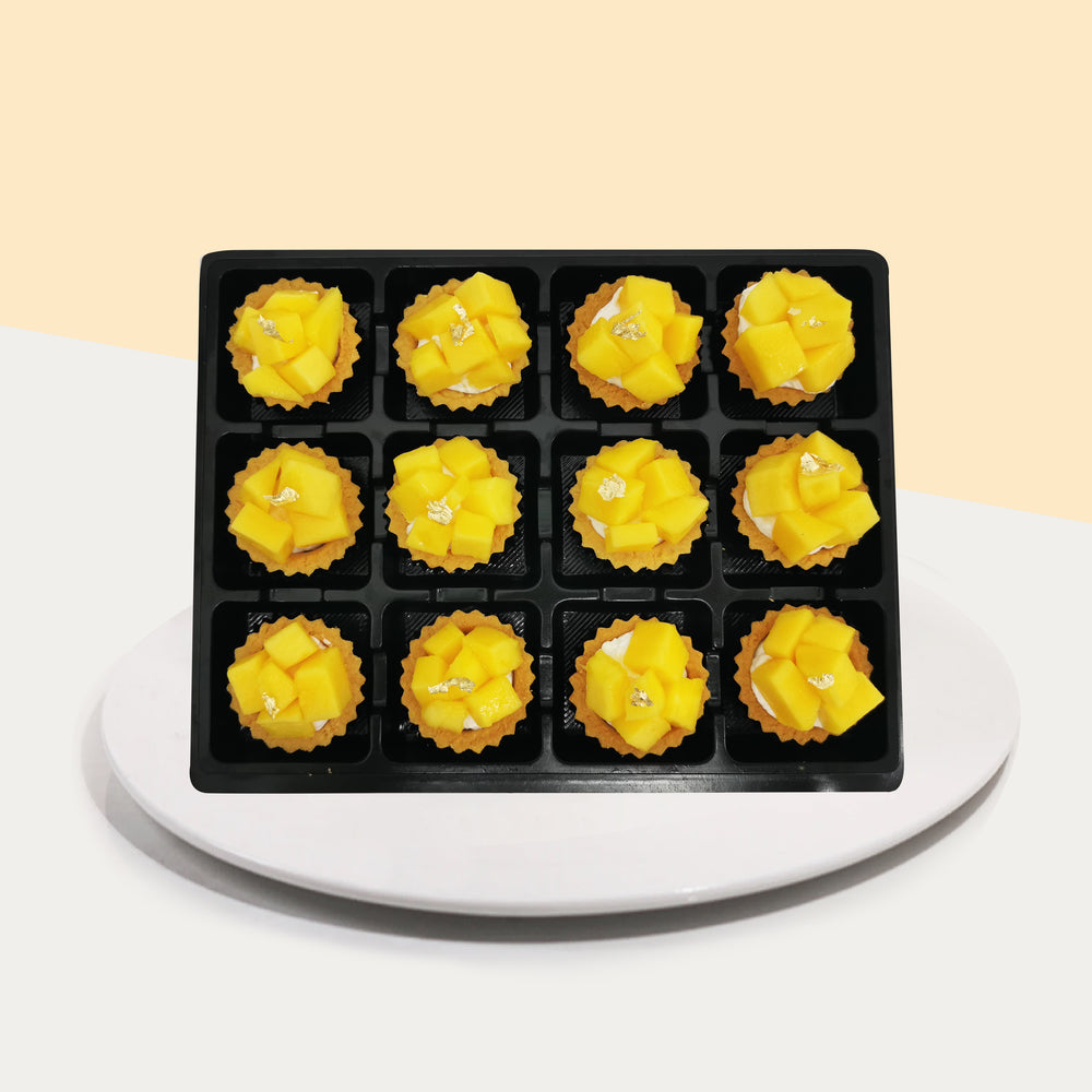 Twelve pieces of mango tarts on a black tray