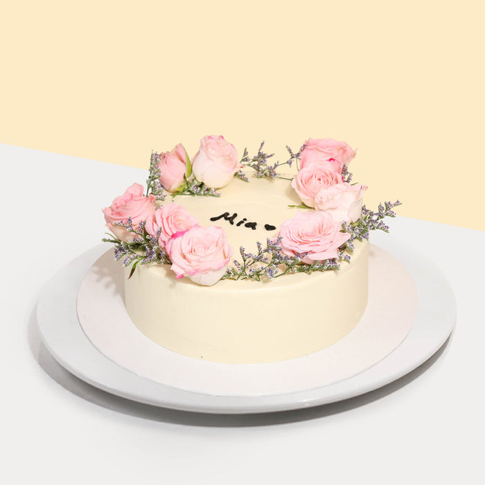 Butter cake coated in buttercream, topped with fresh roses